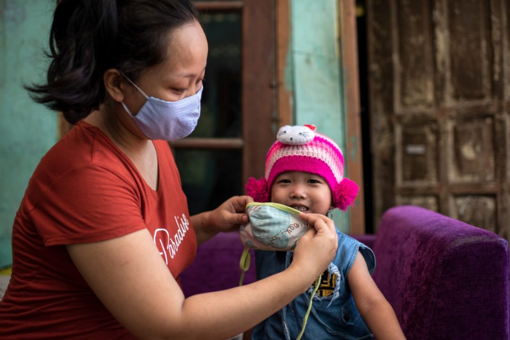 Masa Adaptasi Kebiasaan Baru - Ibu Endah, membantu Fatima, putrinya yang berusia tiga tahun menggunakan masker kain saat akan pergi keluar rumah di daerah Bekasi, Jawa barat 14 Juni 2020. Foto UNICEF/2020/Arimacs Wilander